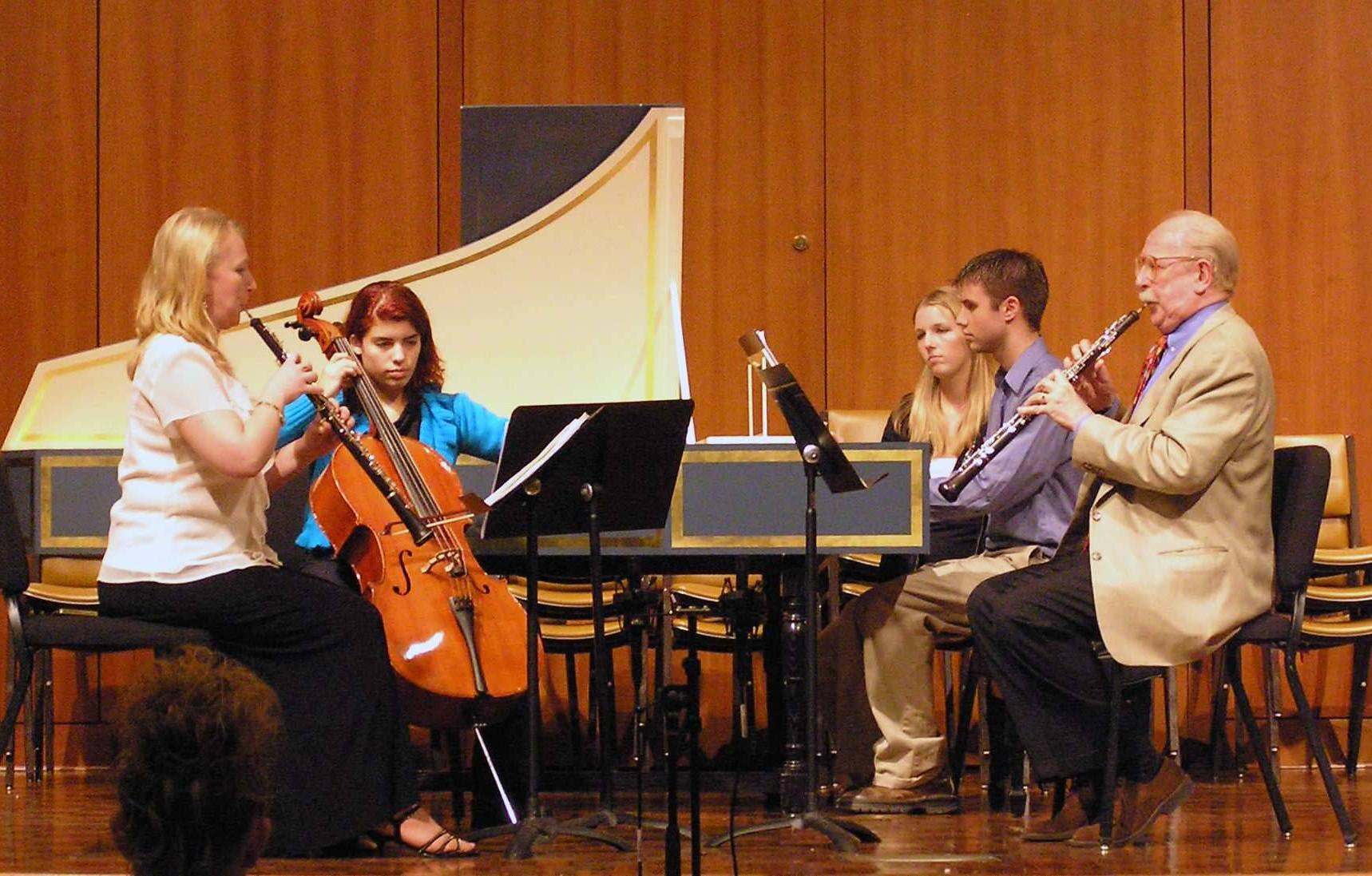 Musicians on the stage playing oboes, cello, and harpsichord.